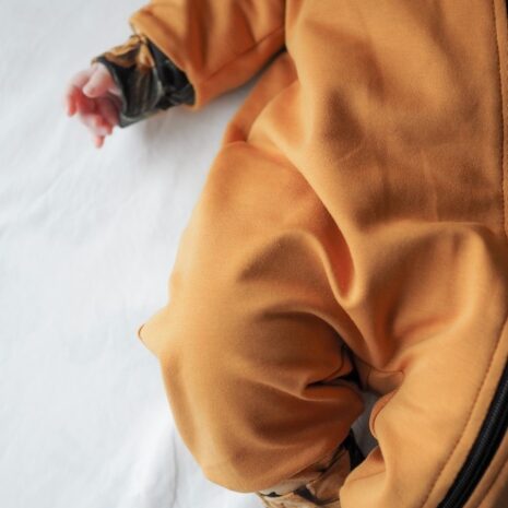Okrassa vauvan jumpsuitissa on kauniina yksityiskohtana lahkeissa ja hihoissa okraa pioni-trikoota.